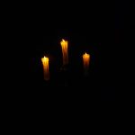 A photograph of three candles in the dark.