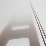 A photograph of a bridge disappearing into fog.