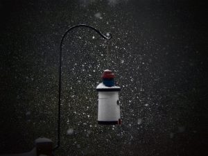 A photograph of a quaint birdhouse surrounded by snowflakes.