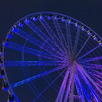 A photograph of a Ferris wheel, lit up at night.