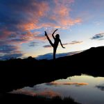 A photograph of a dancer silhouetted against a sunset reflected in a pond.
