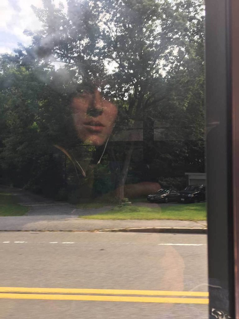 A photograph of a girl reflected in a window.