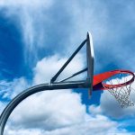 A photograph of a swaying basketball hoop against an interesting sky.
