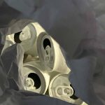 A mixed media image of aluminum cans painted white, seen through crinkled grey paper.