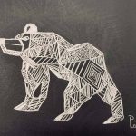 A pencil drawing on black paper of an abstract bear drawn in shapes.