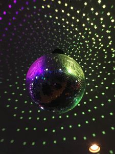 A photograph of a disco ball reflecting pinpricks of multicoloured light.