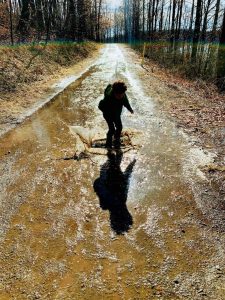 A photograph of a child splashing in a muddy puddle.