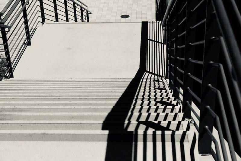 A photograph of the harsh shadows of a railing on some steps.