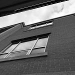 Black and white photograph of a brick building with windows from below