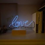 Photograph of a electroluminescent wire sculpture displaying the word "love".
